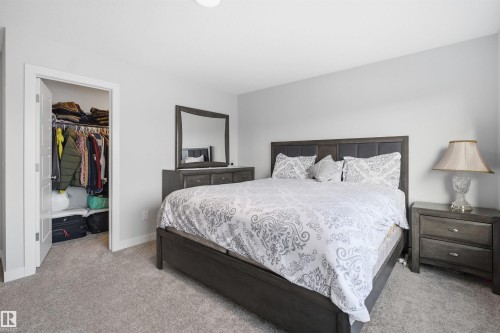 The property features a bedroom with light grey walls, grey carpet, and a closet with a white door - 7017 54 Avenue, Beaumont, AB - Indoor Photo Showing Bedroom