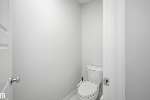 A pristine white toilet is visible in this room, set against light-colored walls, providing a clean and functional space - 7017 54 Avenue, Beaumont, AB - Indoor Photo Showing Bathroom