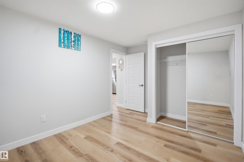 This room features light-toned flooring, a mirrored closet, and a white interior door - 7017 54 Avenue, Beaumont, AB - Indoor Photo Showing Other Room
