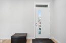 The entryway features a white front door with a vertical glass insert and a transom window, set against light-colored walls and light wood flooring - 7017 54 Avenue, Beaumont, AB  - Indoor Photo Showing Other Room 