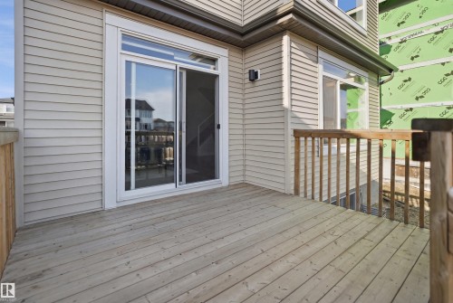The property features a wood deck with a wooden railing and light-colored siding - 7017 54 Avenue, Beaumont, AB - Outdoor With Deck Patio Veranda With Exterior