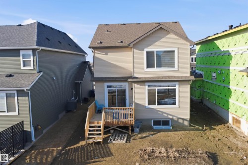 The property features a rear deck with wooden steps and a sliding glass door - 7017 54 Avenue, Beaumont, AB - Outdoor
