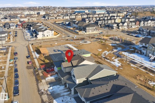 Aerial view showcasing the property within a residential area, surrounded by other homes and a community park with a basketball court - 7017 54 Avenue, Beaumont, AB - Outdoor With View