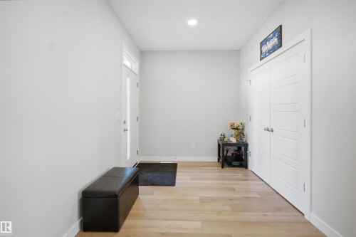 This entry area features light-toned flooring, white walls, and a white entry door with an upper window - 7017 54 Avenue, Beaumont, AB - Indoor Photo Showing Other Room