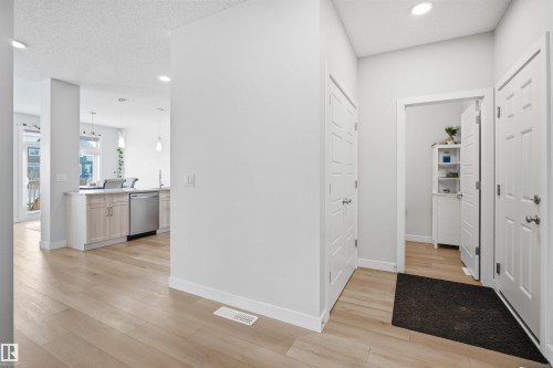 This property features light wood flooring, recessed lighting, white walls, and a contemporary kitchen with light wood cabinetry and stainless steel appliances - 7017 54 Avenue, Beaumont, AB - Indoor Photo Showing Other Room