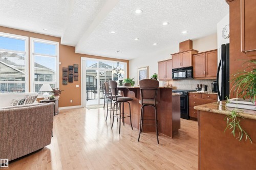 This property features an open living area with light hardwood floors and large windows, providing natural light - 13 841 156 Street, Edmonton, AB - Indoor Photo Showing Kitchen