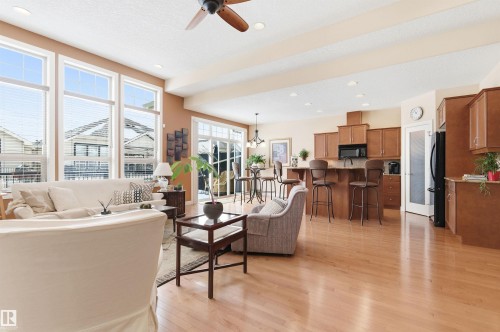 This open-concept living area features hardwood floors, a ceiling fan, and large windows providing natural light - 13 841 156 Street, Edmonton, AB - Indoor Photo Showing Other Room