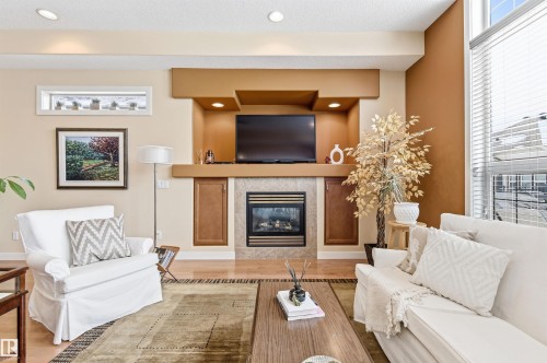 Living area featuring a fireplace with a tiled surround, recessed lighting, and large windows providing natural light - 13 841 156 Street, Edmonton, AB - Indoor Photo Showing Living Room With Fireplace