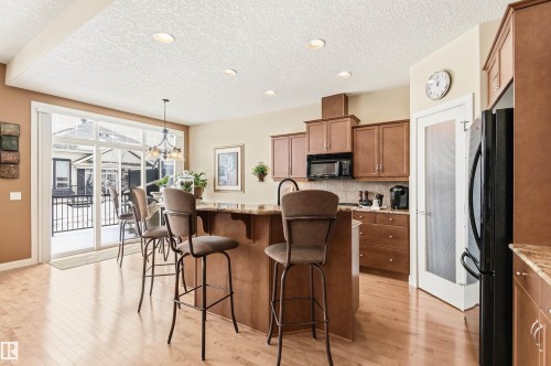The kitchen features hardwood floors, a large island with a granite countertop, and matching wood cabinetry - 13 841 156 Street, Edmonton, AB - Indoor