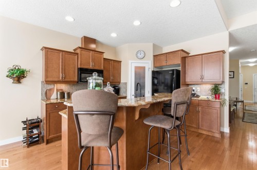 This kitchen features wood cabinetry, granite countertops, and hardwood flooring - 13 841 156 Street, Edmonton, AB - Indoor