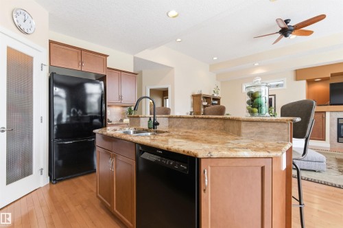 The kitchen features wood cabinetry, a granite countertop, and a black refrigerator and dishwasher - 13 841 156 Street, Edmonton, AB - Indoor Photo Showing Kitchen With Double Sink