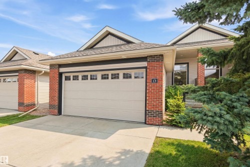 The property features an attached garage with a light-colored garage door and windows along the top - 13 841 156 Street, Edmonton, AB - Outdoor