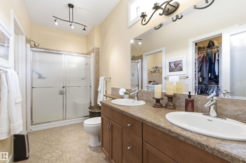 The bathroom features a double vanity with two sinks, a shower with sliding doors, and a built-in closet with shelving and hanging space - 13 841 156 Street, Edmonton, AB - Indoor Photo Showing Bathroom