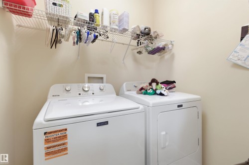 Laundry area featuring a top-load washing machine, a front-load dryer, and wall-mounted wire shelving - 13 841 156 Street, Edmonton, AB - Indoor Photo Showing Laundry Room