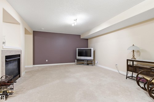 Spacious room featuring carpeting, a fireplace with a stone surround, and an accent wall - 13 841 156 Street, Edmonton, AB - Indoor
