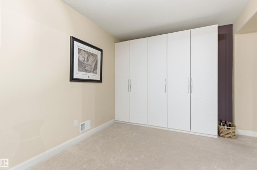 This room features plush carpeting and a wall of integrated white wardrobes, offering extensive storage solutions - 13 841 156 Street, Edmonton, AB - Indoor Photo Showing Other Room