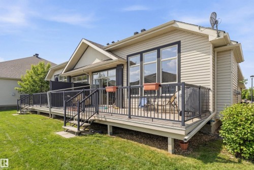 The property features an elevated deck with black railings and two sets of stairs leading to a well-maintained lawn - 13 841 156 Street, Edmonton, AB - Outdoor With Deck Patio Veranda
