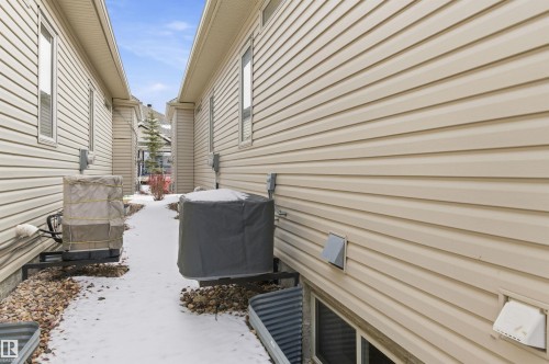 The property features light-colored horizontal siding, visible windows, and a paved path - 13 841 156 Street, Edmonton, AB - Outdoor With Exterior