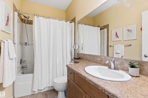 The bathroom features a vanity with a large mirror, an integrated sink, and a bathtub with a shower - 13 841 156 Street, Edmonton, AB - Indoor Photo Showing Bathroom