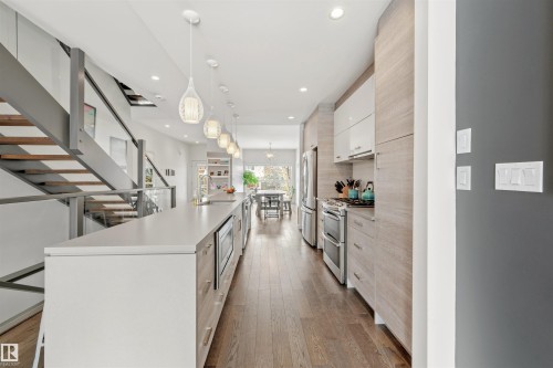 Open-concept kitchen featuring an expansive island with an integrated microwave, stainless steel appliances, and a range hood - 10607 127 Street, Edmonton, AB - Indoor Photo Showing Kitchen With Upgraded Kitchen