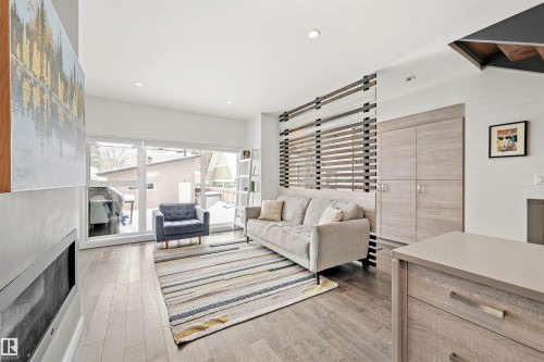 Living area featuring hardwood floors, large windows with natural light, and a built-in storage unit - 10607 127 Street, Edmonton, AB - Indoor Photo Showing Living Room