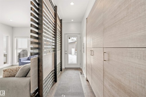 The entryway features built-in storage cabinets with modern handles and a decorative slatted partition - 10607 127 Street, Edmonton, AB - Indoor Photo Showing Other Room