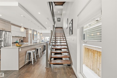 Open concept living space featuring hardwood floors, a contemporary kitchen with a long island, and modern pendant lighting - 10607 127 Street, Edmonton, AB - Indoor Photo Showing Other Room