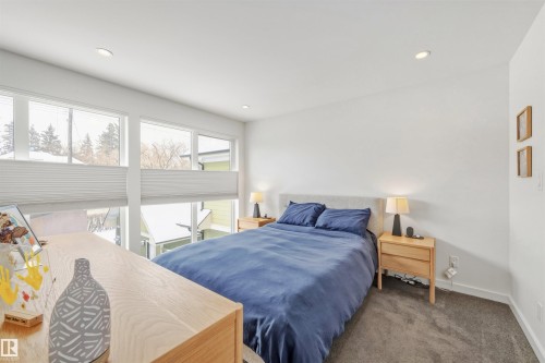 This room features expansive windows with white blinds, recessed lighting, and soft carpet flooring - 10607 127 Street, Edmonton, AB - Indoor Photo Showing Bedroom