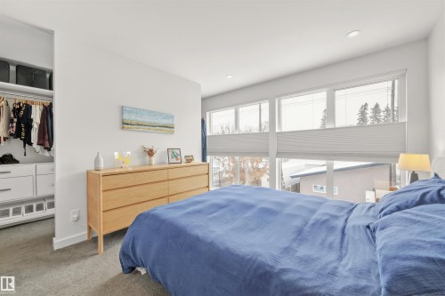 This bedroom features expansive windows with blinds, a built-in closet with shelving and hanging space, and recessed lighting - 10607 127 Street, Edmonton, AB - Indoor Photo Showing Bedroom