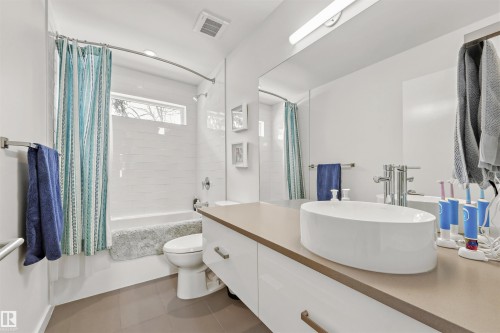 The bathroom features a modern vessel sink, a vanity with drawers, a bathtub with white subway tile surround, and a large mirror - 10607 127 Street, Edmonton, AB - Indoor Photo Showing Bathroom