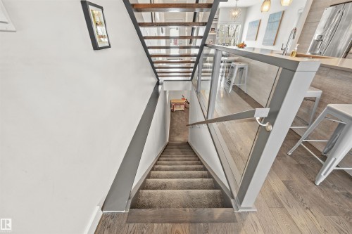 Modern staircase with glass panel railing and wooden treads, leading to a lower level - 10607 127 Street, Edmonton, AB - Indoor Photo Showing Other Room