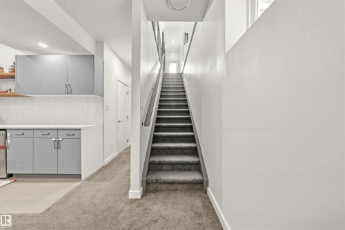 The property features a staircase with carpeted steps and a modern railing, complemented by light-colored walls - 10607 127 Street, Edmonton, AB - Indoor Photo Showing Other Room