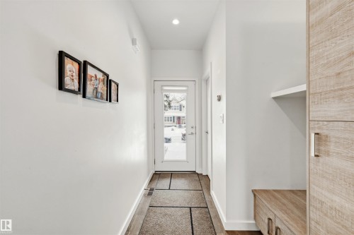 Entryway featuring light-colored flooring, a white door with frosted glass, and built-in storage with a light wood finish - 10607 127 Street, Edmonton, AB - Indoor Photo Showing Other Room