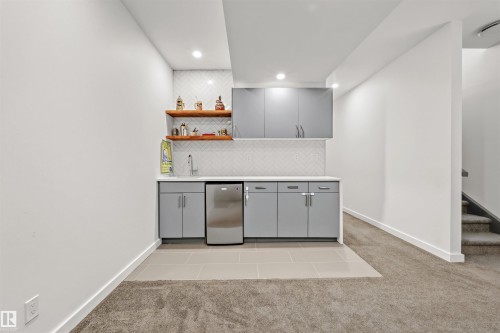 Wet bar area featuring light gray cabinetry, a stainless steel mini-fridge, and a white herringbone tile backsplash - 10607 127 Street, Edmonton, AB - Indoor