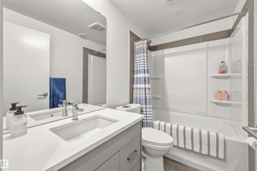 The bathroom features a vanity with an integrated sink, a large wall-mounted mirror, and a bathtub with a shower kit - 10607 127 Street, Edmonton, AB - Indoor Photo Showing Bathroom