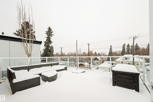 Rooftop terrace featuring a glass railing and a view of surrounding structures and trees - 10607 127 Street, Edmonton, AB - Outdoor