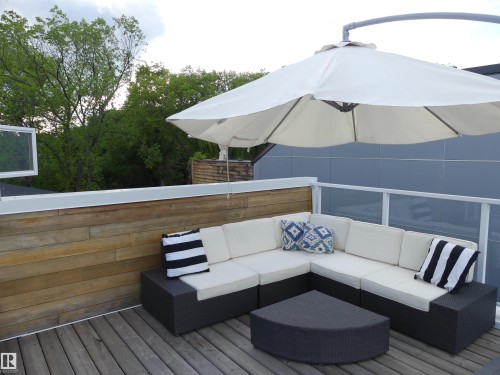 The property features an outdoor patio with wood decking, a privacy wall with horizontal wood paneling, and a contemporary glass and metal railing - 10607 127 Street, Edmonton, AB - Outdoor With Deck Patio Veranda