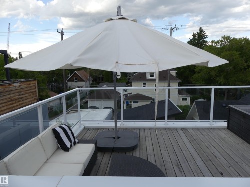 Expansive rooftop deck featuring wood decking and glass railings, offering views of the surrounding area - 10607 127 Street, Edmonton, AB - Outdoor With Deck Patio Veranda