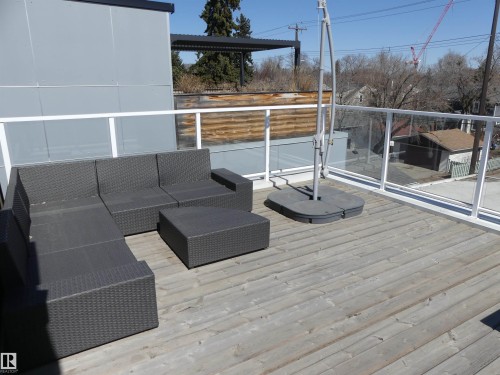 Rooftop deck featuring wooden planks, a glass and white railing, and an umbrella base - 10607 127 Street, Edmonton, AB - Outdoor With Deck Patio Veranda With Exterior