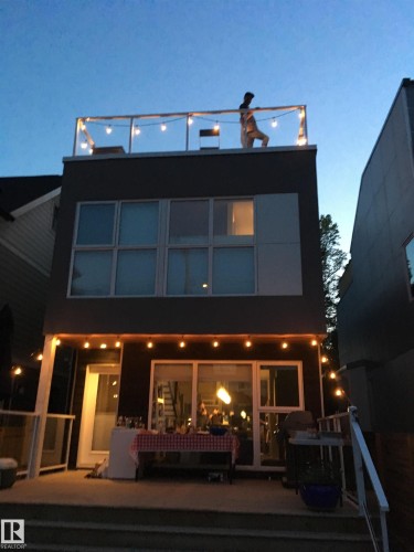 The property features a rooftop deck with string lighting and a glass railing, as well as a patio with string lighting and a railing - 10607 127 Street, Edmonton, AB - Outdoor