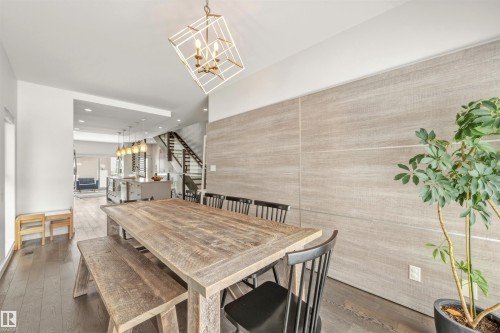 The dining area features dark wood floors, a distressed wood table with benches, and a unique geometric pendant light fixture - 10607 127 Street, Edmonton, AB - Indoor