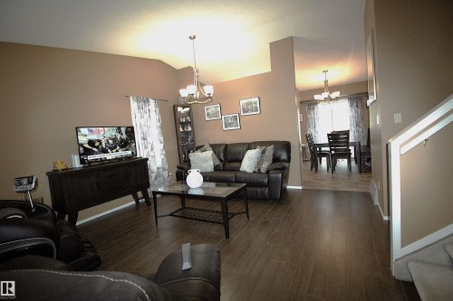 The living area features vaulted ceilings, dark wood-look flooring, and a chandelier - 9347 175 Avenue, Edmonton, AB - Indoor Photo Showing Living Room