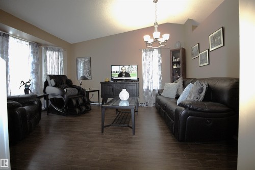 The living area features vaulted ceilings, dark wood-look flooring, and a chandelier light fixture - 9347 175 Avenue, Edmonton, AB - Indoor Photo Showing Living Room