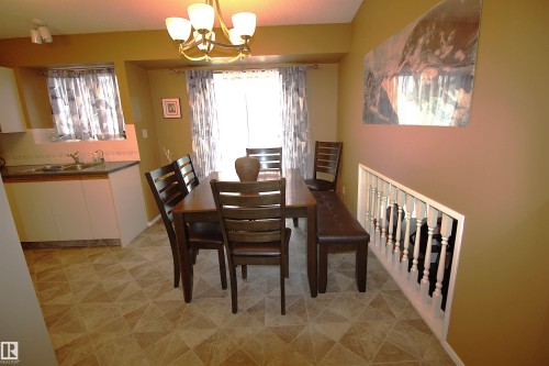 Dining area with a chandelier and patterned floor tiles, offering access to a kitchen area with a sink and window - 9347 175 Avenue, Edmonton, AB - Indoor Photo Showing Dining Room
