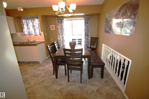 Dining area featuring a dining table with chairs and a bench, patterned flooring, and a sliding glass door leading to the outdoors - 9347 175 Avenue, Edmonton, AB - Indoor Photo Showing Dining Room