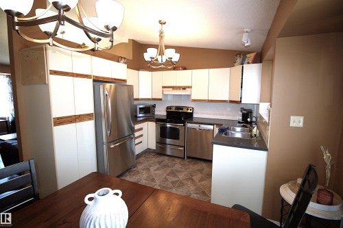 The kitchen features white cabinetry, stainless steel appliances, a double basin sink, and patterned flooring - 9347 175 Avenue, Edmonton, AB - Indoor Photo Showing Kitchen With Double Sink
