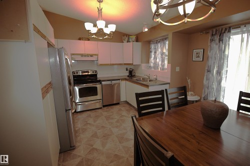 The kitchen features white cabinetry, stainless steel appliances, and a patterned floor - 9347 175 Avenue, Edmonton, AB - Indoor