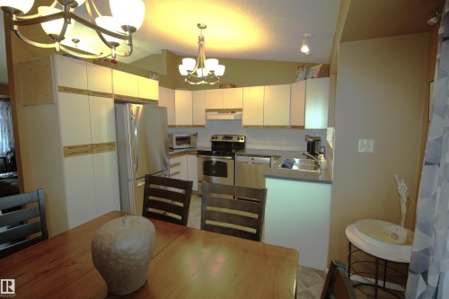 This kitchen features white cabinetry, stainless steel appliances, and a double basin sink - 9347 175 Avenue, Edmonton, AB - Indoor