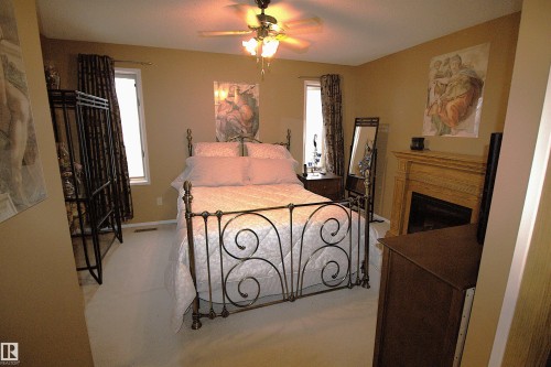 This room features light-colored carpeting, a ceiling fan with integrated lighting, and a fireplace with a detailed wooden mantel - 9347 175 Avenue, Edmonton, AB - Indoor