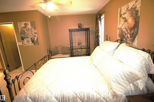 This room features warm-toned walls, a ceiling fan with integrated lighting, and a window with curtains - 9347 175 Avenue, Edmonton, AB - Indoor Photo Showing Bedroom